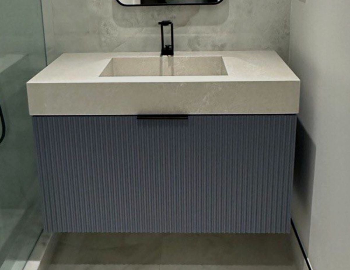 Fluted navy floating bathroom vanity with an integrated stone countertop by KABCO