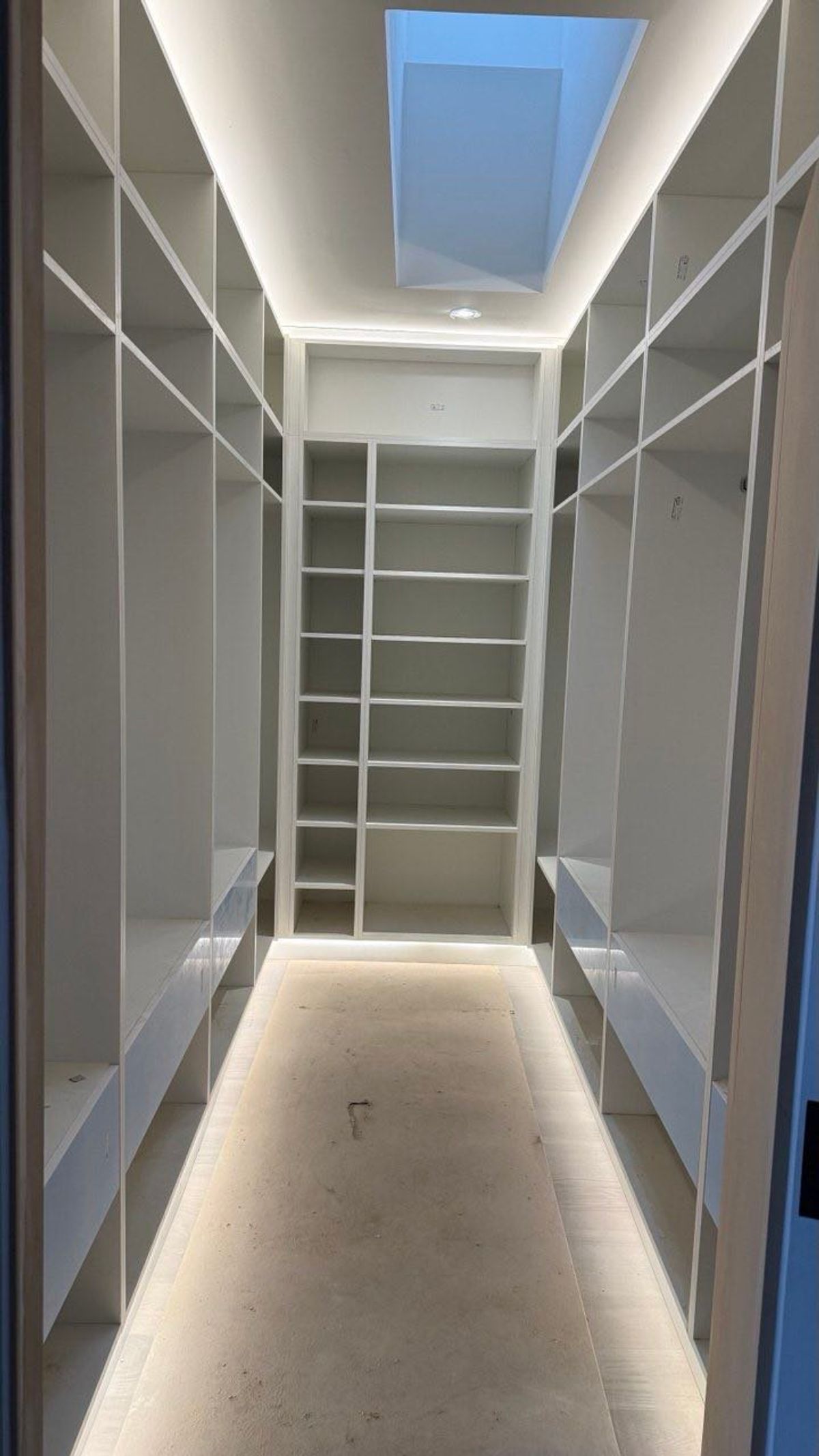 Custom walk-in closet with open shelving, drawers and a skylight during installation by KABCO