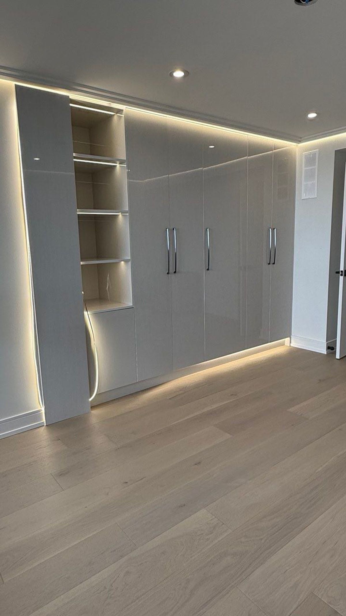 Floor-to-ceiling white gloss closet cabinetry with integrated LED lighting in a Vaughan home