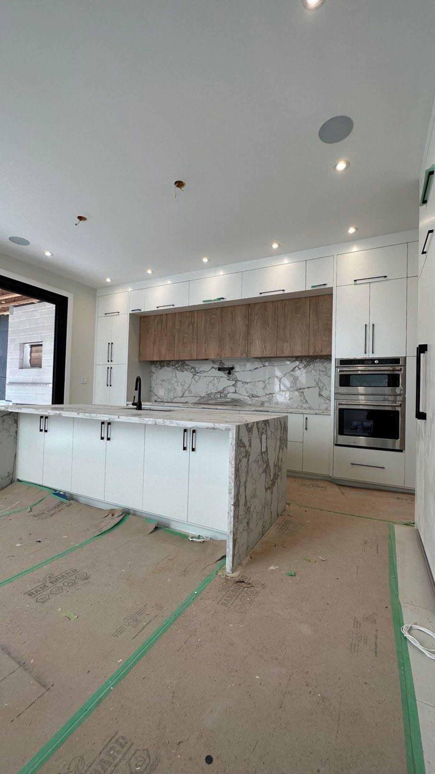 Lumia — white laundry cabinets with a marble-look counter during installation by KABCO