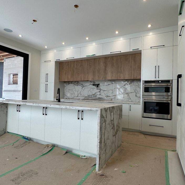 a kitchen with white cabinets and marble counter tops